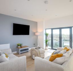 A living room with sofas cushions television and plants at Bryn Min Manton Apartment in Caernarfon