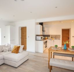 An open plan lounge and kitchen with a sofa and dining table at Bryn Min Manton Bach in Caernarfon
