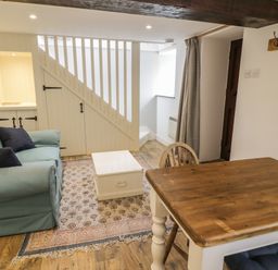 A living room with a blue sofa a wooden table and a white chest under stairs at Gelli Bach at Gelli Las in Llanbedr