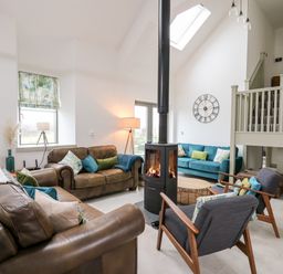 A living room with leather sofas a wood stove and a teal couch at Ysgoldy Brynwyre in Llanrhystud