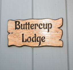 A wooden sign with the text Buttercup Lodge mounted on a gray wall at Buttercup Lodge in Misterton