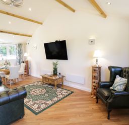 A living room with green leather armchairs a wooden coffee table a dining table with chairs and curtains at FAIRFIELD in Clee Hill