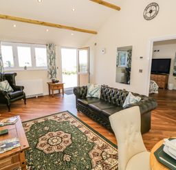 A living room with a green leather sofa armchair wooden furniture and a patterned rug at FAIRFIELD in Clee Hill