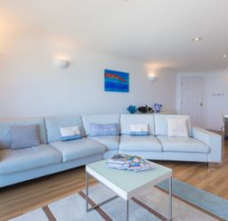 A living room with a light blue sofa and a coffee table with magazines at Turquarze in Carbis Bay