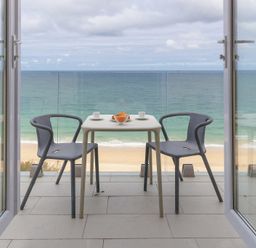 A balcony with two chairs and a table overlooking the ocean at Turquarze in Carbis Bay