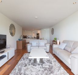A living room with white sofas a white coffee table and a television at Abalone in St Ives
