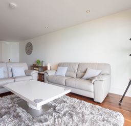 A living room with two sofas a white coffee table a telescope and a wall clock at Abalone in St Ives