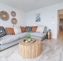 A living room with a gray sectional sofa and a round wooden coffee table at Atlantic Watch 8 in Carbis Bay