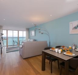 A living room with dining table set for breakfast and ocean view at Elanora in Carbis Bay