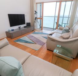 A living room with sofas a glass side table a wall mounted TV a patterned rug and a telescope facing the ocean at Elanora in Carbis Bay