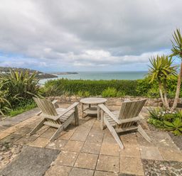 A patio area with chairs and a table overlooking the sea at Island View in Carbis Bay