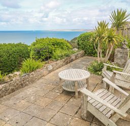 An outdoor seating area with wooden furniture and a sea view at Island View in Carbis Bay
