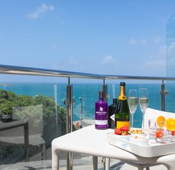 A balcony table with drinks and snacks overlooking the sea with glass and metal railing at Portside in Carbis Bay