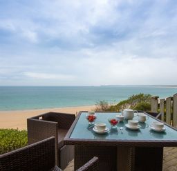 A patio table with tea set and bowls of strawberries overlooking a sandy beach and ocean at Sapphire in Carbis Bay