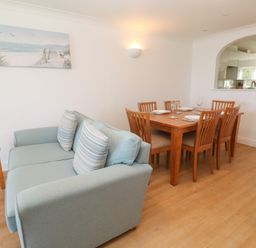 A dining area with a wooden table set for six people next to a light blue sofa in a room at Sapphire in Carbis Bay