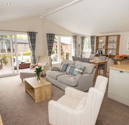 An open living room and dining area with sofas armchairs a wooden coffee table and dining table at Seagull Lodge in Runswick Bay