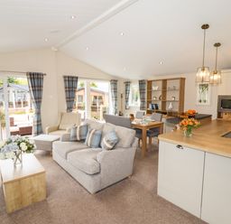 A living room with sofa armchair dining table and kitchen area at Seagull Lodge in Runswick Bay