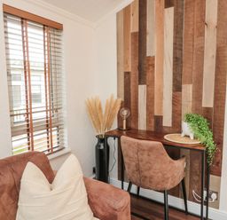 A corner with a wooden desk and chair near a window with wooden blinds at Woodland View Lodge Swarland near Felton