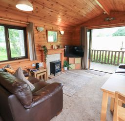 A living room with a sofa, table, and fireplace at Squirrels Leap, Number 29, Burnside Park near Keswick