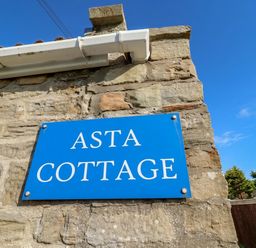 A sign on a stone wall at ASTA COTTAGE in Cresswell