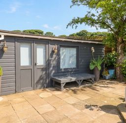 A garden view featuring a cabin with a bench and planters at ASTA COTTAGE Cresswell