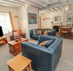 A living room with blue leather sofas a brown armchair a wooden coffee table and a dining area at Woolley Lodge in Wooler