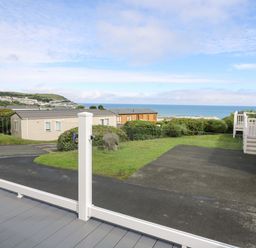 A view of mobile homes with a road grass and the sea in the background at The Potting Shed in New Quay