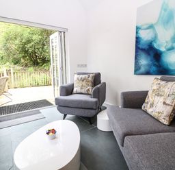 A living room with gray armchairs and a sofa with patterned cushions and a white coffee table with candy at Twigs in Woody Bay