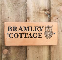 A wooden sign with an owl illustration and the text Bramley Cottage on a wooden background at Bramley Cottage in Henley near Langport
