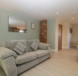 A living room with two sofas a mirror and a brick column at Bramley Cottage Henley near Langport