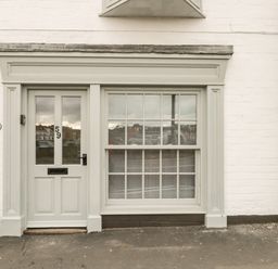 A white front door with number 59 and a window next to it on a white brick building at Swallows Nest in Whitby