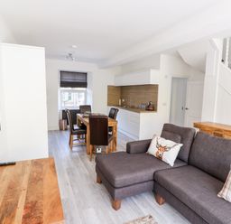 A living room with a gray sofa and wooden table next to a dining area with wooden table and chairs at 8 Waterhead Terrace Ambleside