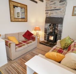 A sitting room with two sofas near a fireplace and a rug on the floor at Dolwen in Penmachno