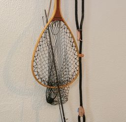 A fishing net and rod hanging on a textured wall at Dolwen in Penmachno