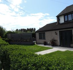 A front yard with green lawn bushes walkway and a two story house at 26 Hycemoor Way Bootle Near Millom