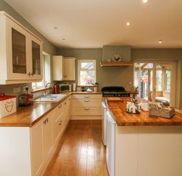 A kitchen with wooden countertops white cabinets and appliances at Nattaden @ Fourwinds in Meldon near Okehampton