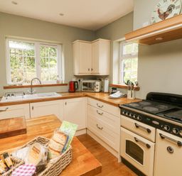 A kitchen with wooden countertops and cream cabinets at Nattaden @ Fourwinds Meldon near Okehampton