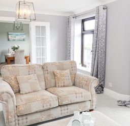A living room with patterned sofa coffee table and grey curtains at 12 Claremont Falls Polperro