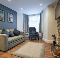 A living room with sofa armchair rug fireplace and TV at Lower Sheriff's Place in Windermere