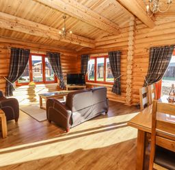 A living room with wooden furniture and a television in a log cabin at Holly Lodge in Greetham Rutland