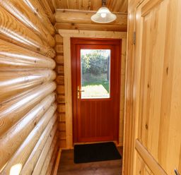 A wooden hallway with a red door and a light fixture at Pine Lodge in Greetham Rutland