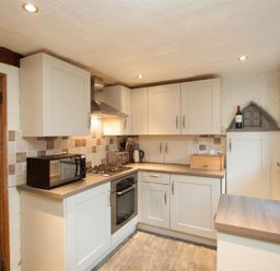A kitchen with cabinets microwave oven kettle bread box and wine bottle at Rustic Cottage in Bowness-On-Windermere