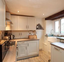 A kitchen with white cabinets a microwave kettle stove and a window at Rustic Cottage in Bowness-On-Windermere
