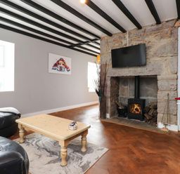 A living room with a sofa, coffee table, television and fireplace at Tyddyn Elidir near Old Colwyn