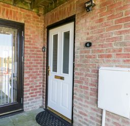 A front door with a mail slot and adjacent glass double doors on a brick wall at Esk View in Whitby