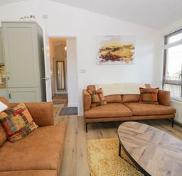 A living room with two brown sofas a wooden coffee table and large window at Broad Oak Lodge Applethwaite 7 Limefitt Park near Windermere