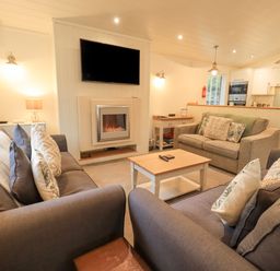 A living room with sofas a coffee table a wall-mounted television and an electric fireplace at Cherry Tree Lodge Calgarth 37 White Cross Bay near Windermere