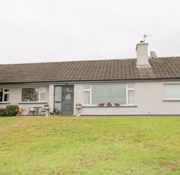 A exterior view of a single story house with a tiled roof and a lawn at 27 Pinewood Hill in Warrenpoint Northern Ireland