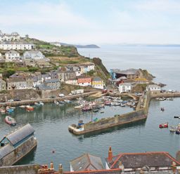 A harbor with boats and houses on a hillside overlooking the sea at Wheal Kendall in Mevagissey