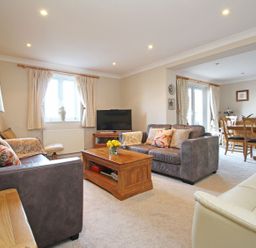 A living room with sofas and a coffee table connected to a dining area with a table and chairs at Wheal Kendall in Mevagissey